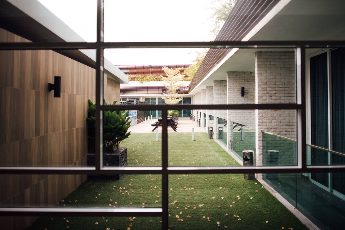 A modern building with a courtyard, glass railings, and a wooden wall.