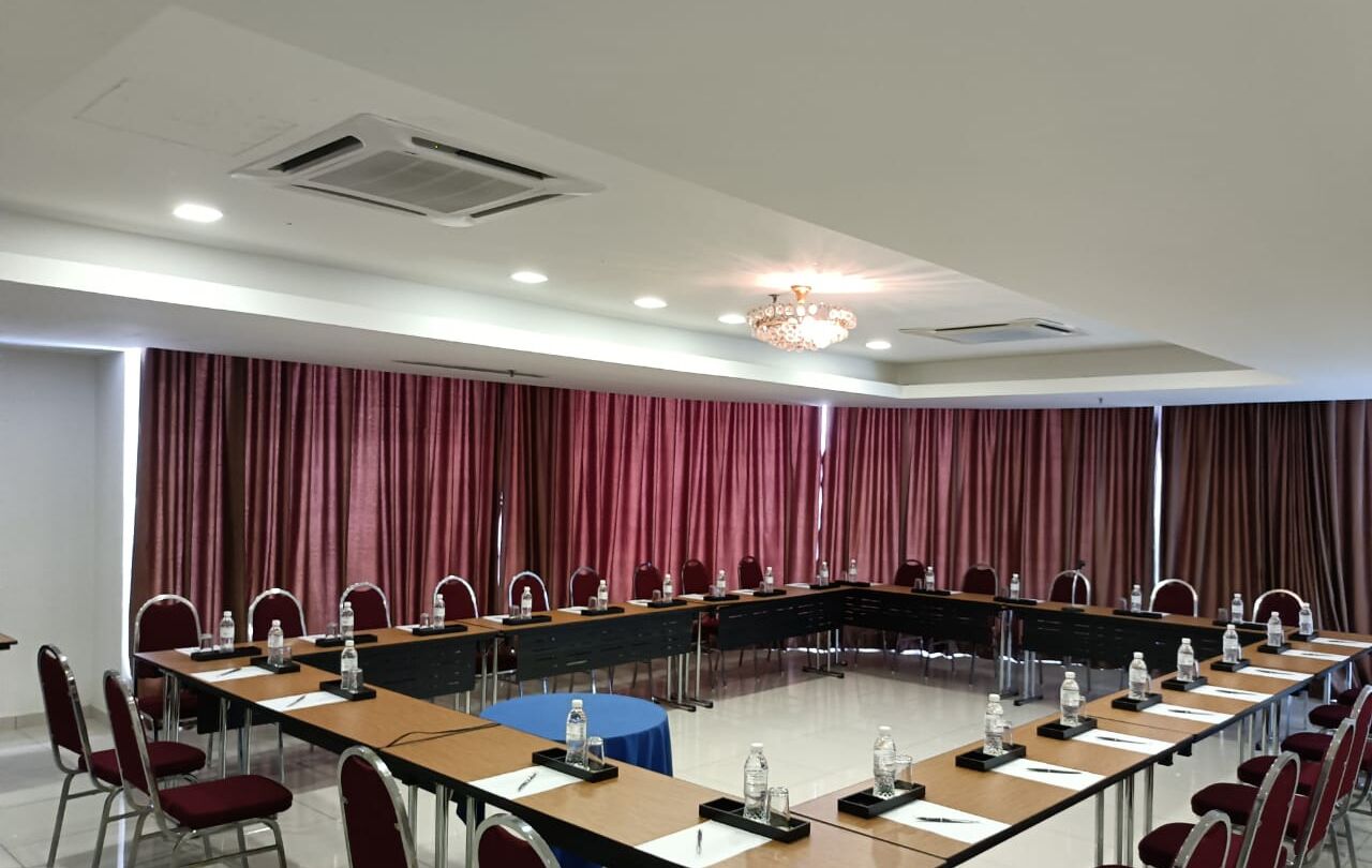 A conference room with a long table, chairs, nameplates, water bottles, and a chandelier.