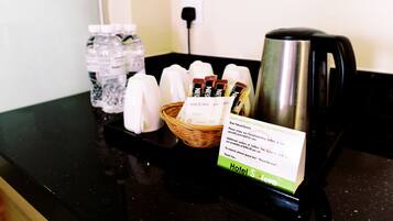 A coffee station with a kettle, sugar packets, and a basket of napkins.