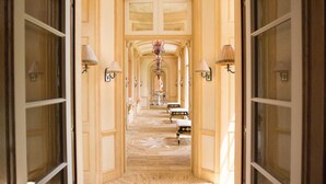 Un vaste hall d’entrée, orné d’un motif complexe sur le sol, mène à une pièce dotée d’une grande fenêtre et d’un lustre.
