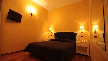 Habitación de hotel con cama, mesitas de noche, lámparas, televisor de pantalla plana y espejo.