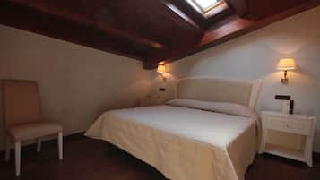 Ein Schlafzimmer mit Bett, Sessel, Nachttisch und einem Oberlicht.