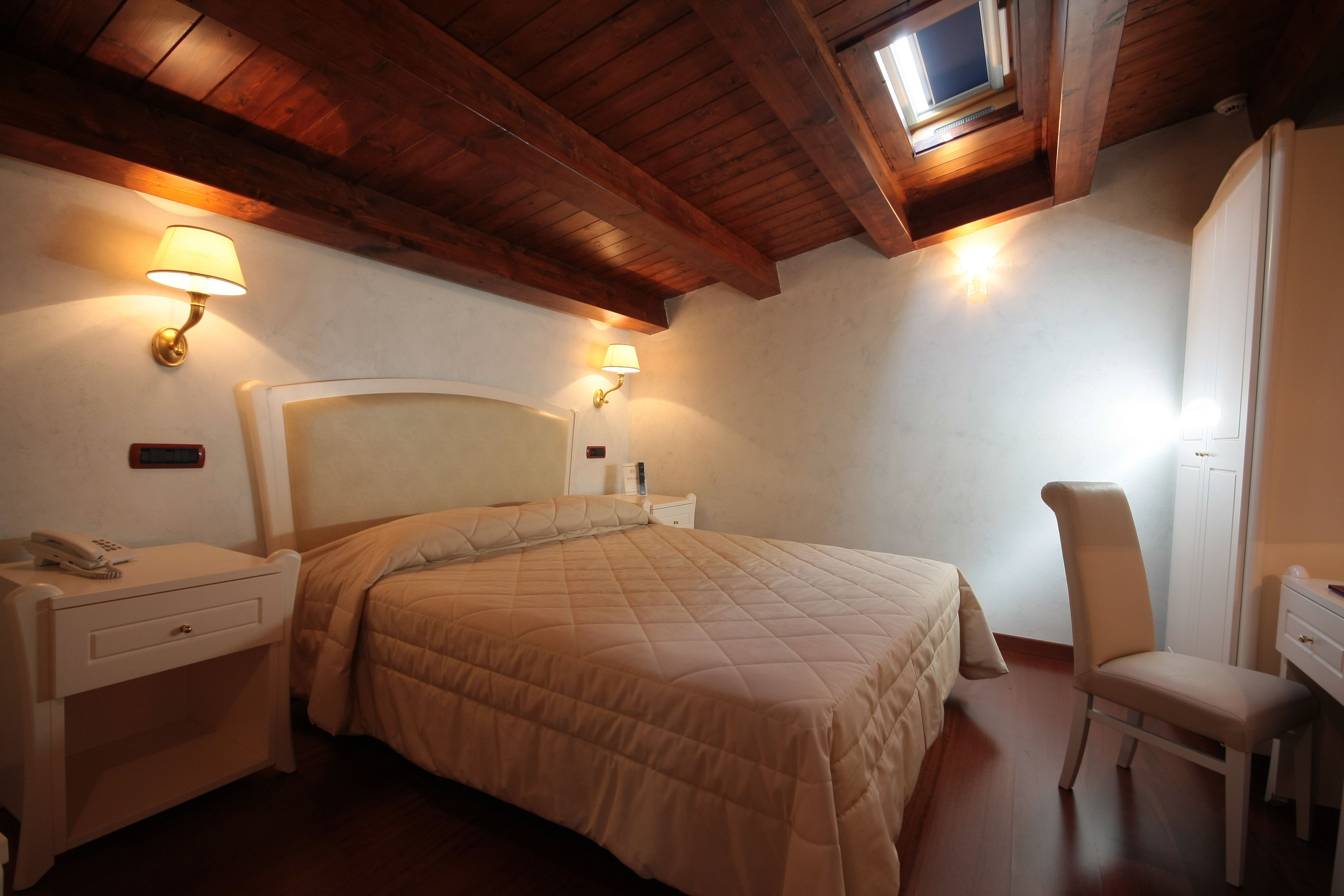 Un dormitorio con una cama grande, lámparas de noche, un escritorio y una silla.