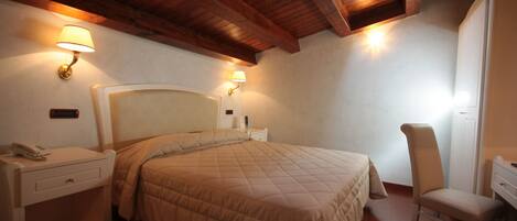 A bedroom with a large bed, bedside lamps, a desk, and a chair.