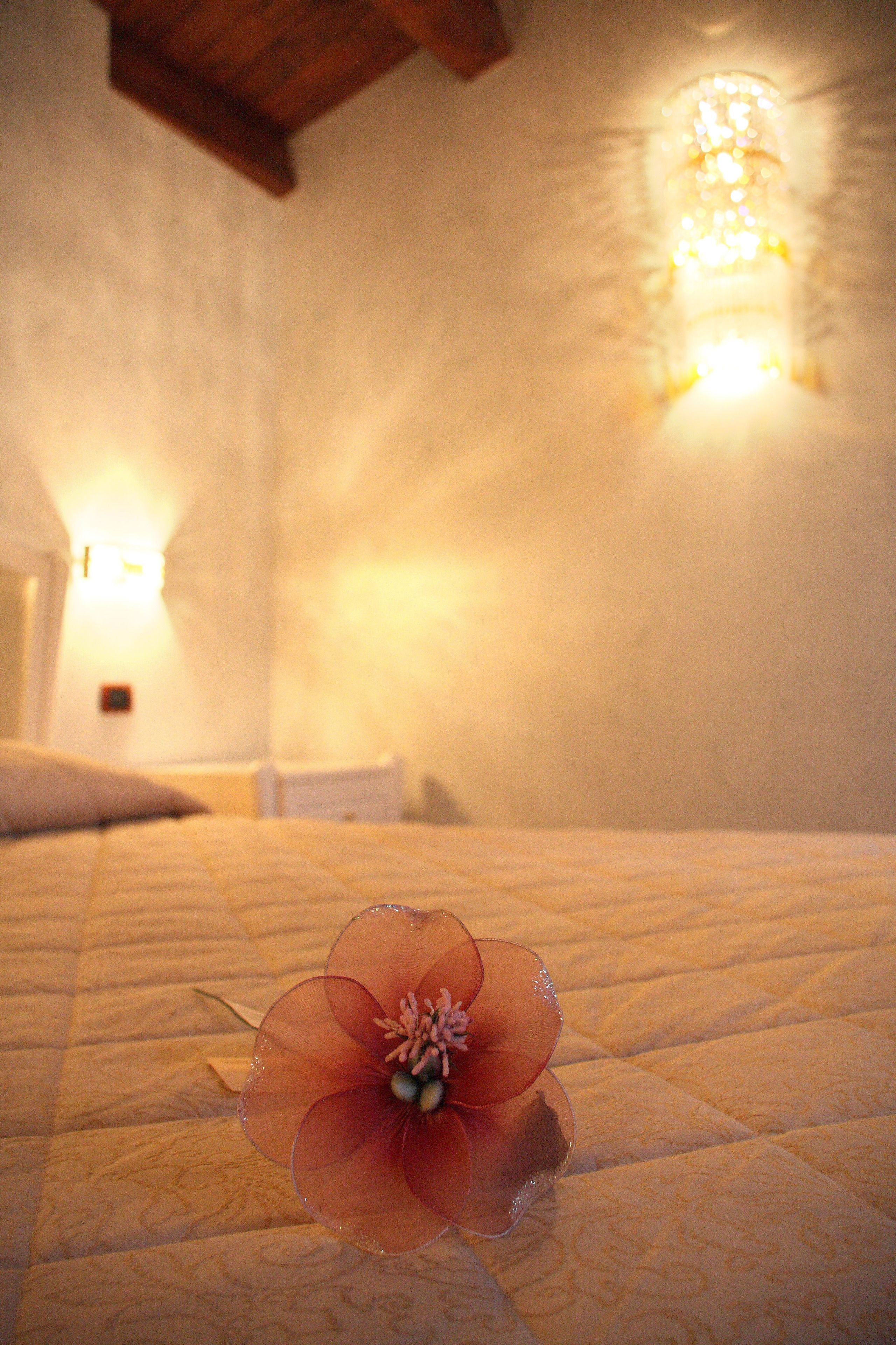 A bed with a decorative flower in the center, a wall-mounted light fixture, and a textured wall.
