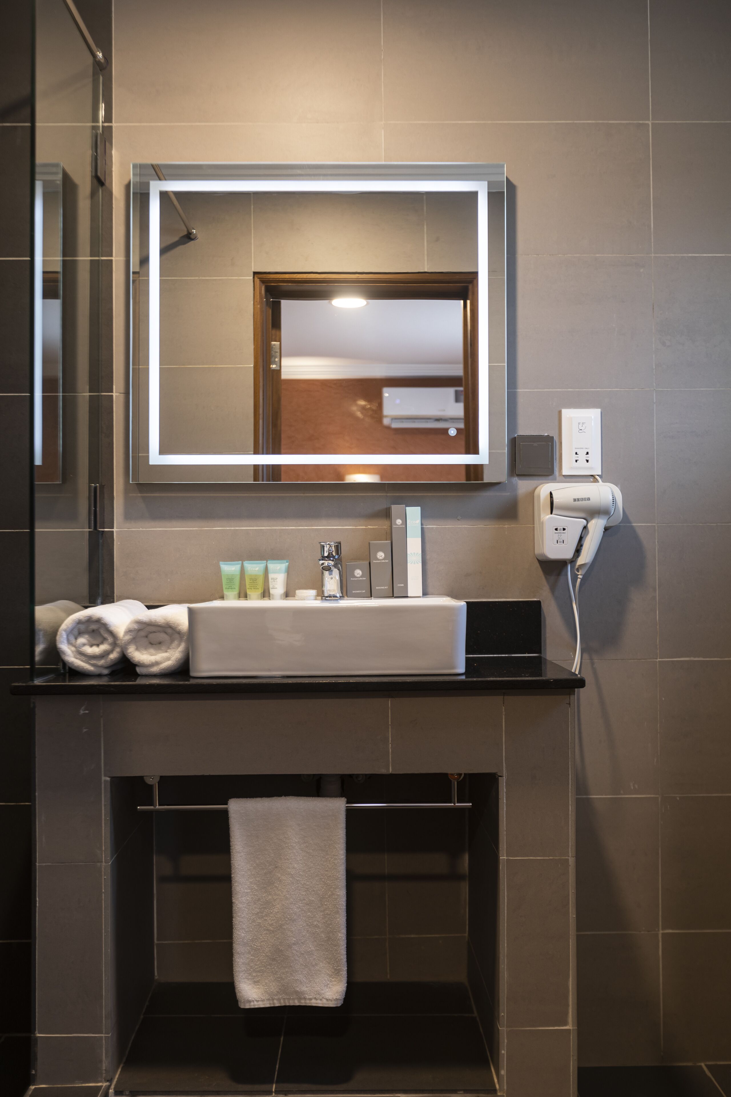 A modern bathroom with a large mirror, a sink, and a towel rack.