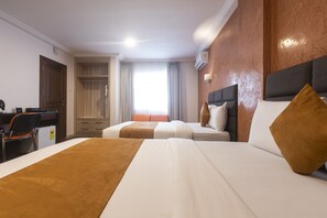 A hotel room with two beds, a desk, a chair, and a wardrobe. - Airport View Hotel (Accra)