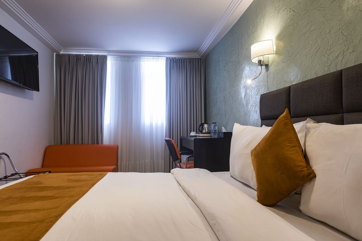 Deluxe kamer | Luxe beddengoed, een minibar, een kluis op de kamer, een bureau
