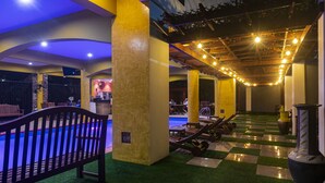 A pool area with artificial grass, lounge chairs, and a checkered floor pattern.
