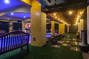 Una piscina techada, sombrillas, sillones reclinables de piscina