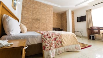 A hotel room with a bed, bedside table, and a desk with a chair.
