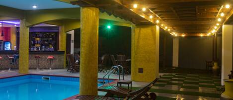 A pool area with lounge chairs, a bar, and a checkered floor.
