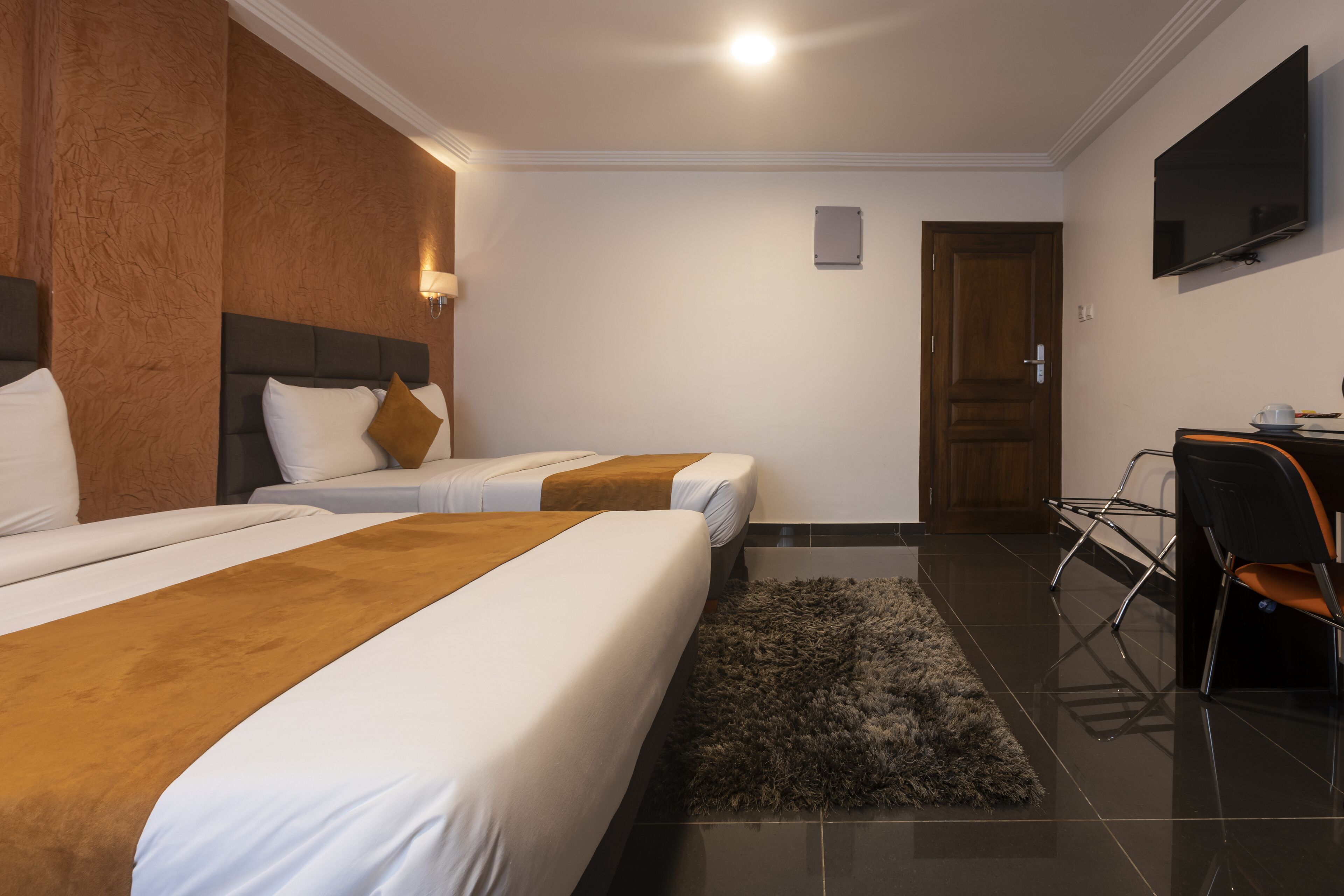 A hotel room with two beds, a TV, a desk, and a chair.