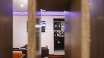 A modern hotel lobby with a reception desk, seating area, and a bar.