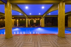 Una piscina cubierta, sombrillas, tumbonas