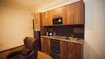 A compact kitchen with wooden cabinets, a built-in microwave, a coffee maker, and a sink.