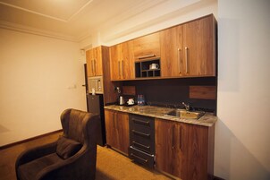 A compact kitchen with wooden cabinets, a built-in microwave, a coffee maker, and a sink.