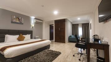 A hotel room with a large bed, a desk, a chair, and a TV.