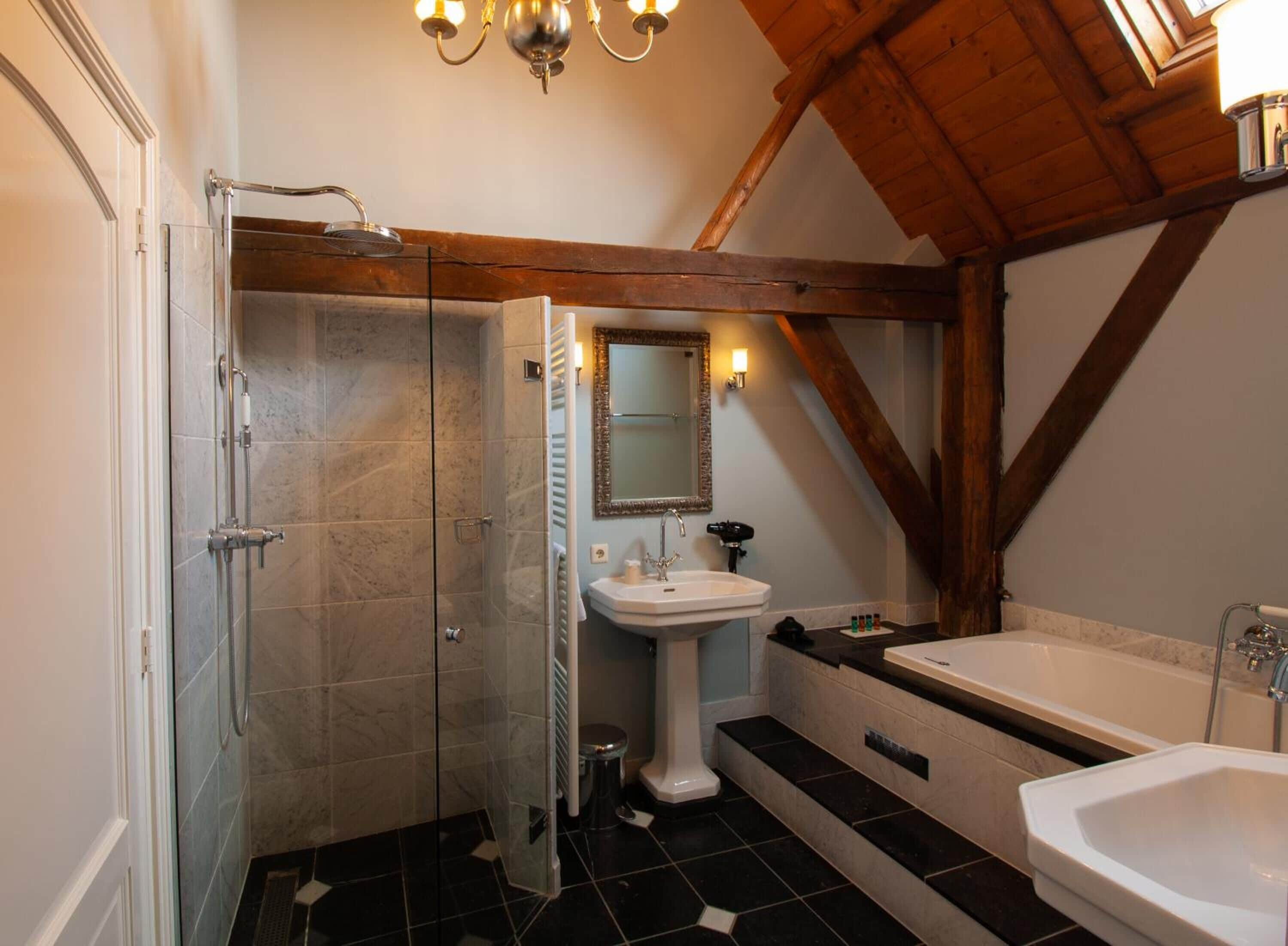 Un baño con ducha de vidrio, lavamanos pedestal, tocador con espejo y bañera.