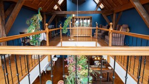 Un loft amplio con escalera de madera, una araña y vista al área de estar inferior.