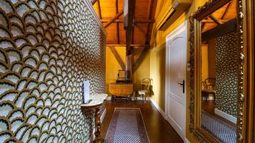 A hallway with a patterned wall, a mirror, a door, and a small table with a chair.