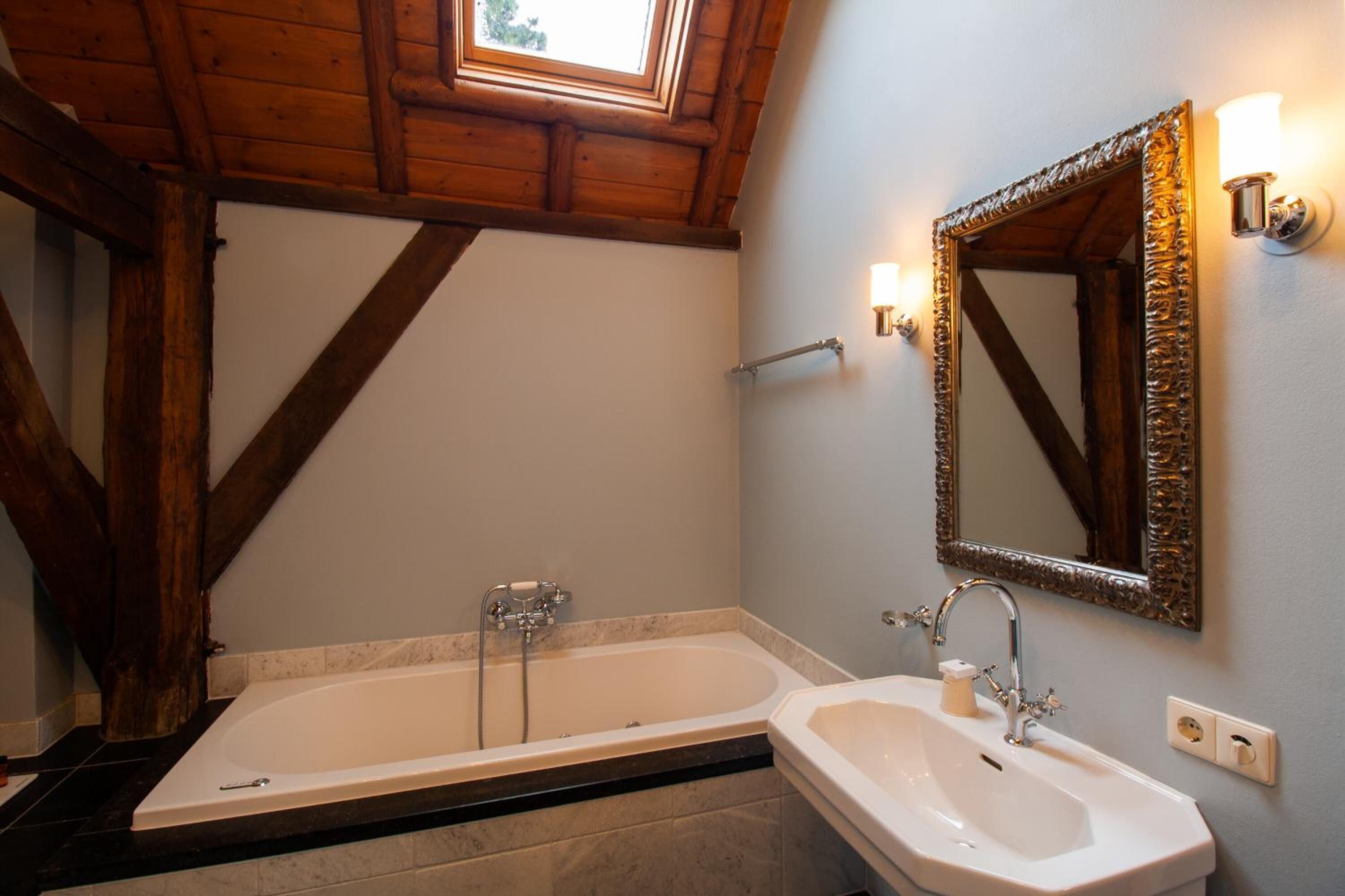 A bathroom with a freestanding bathtub, a sink, and a large mirror.