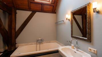 A bathroom with a freestanding bathtub, a sink, and a large mirror.