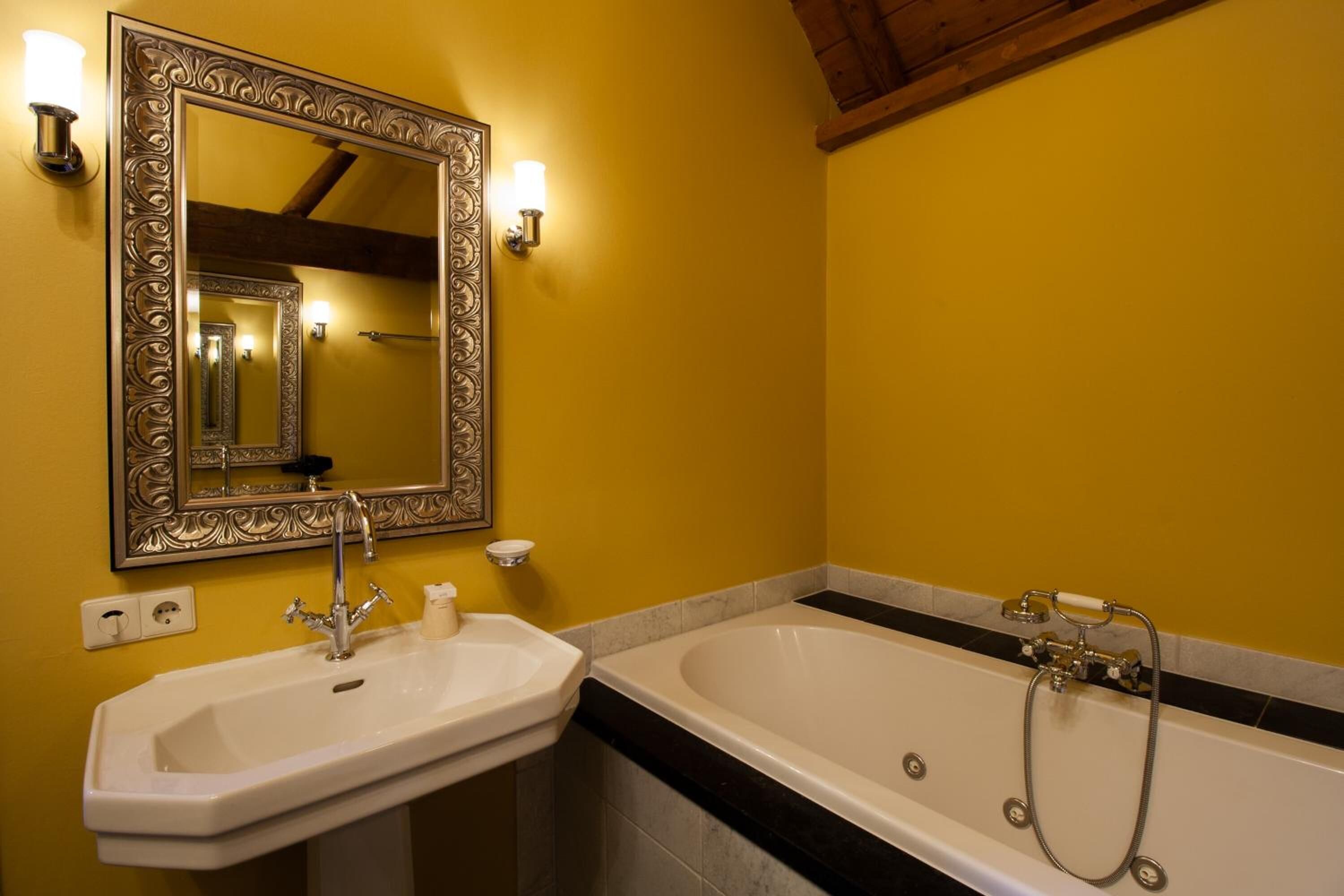 Een badkamer met een wastafel, spiegel en bad.