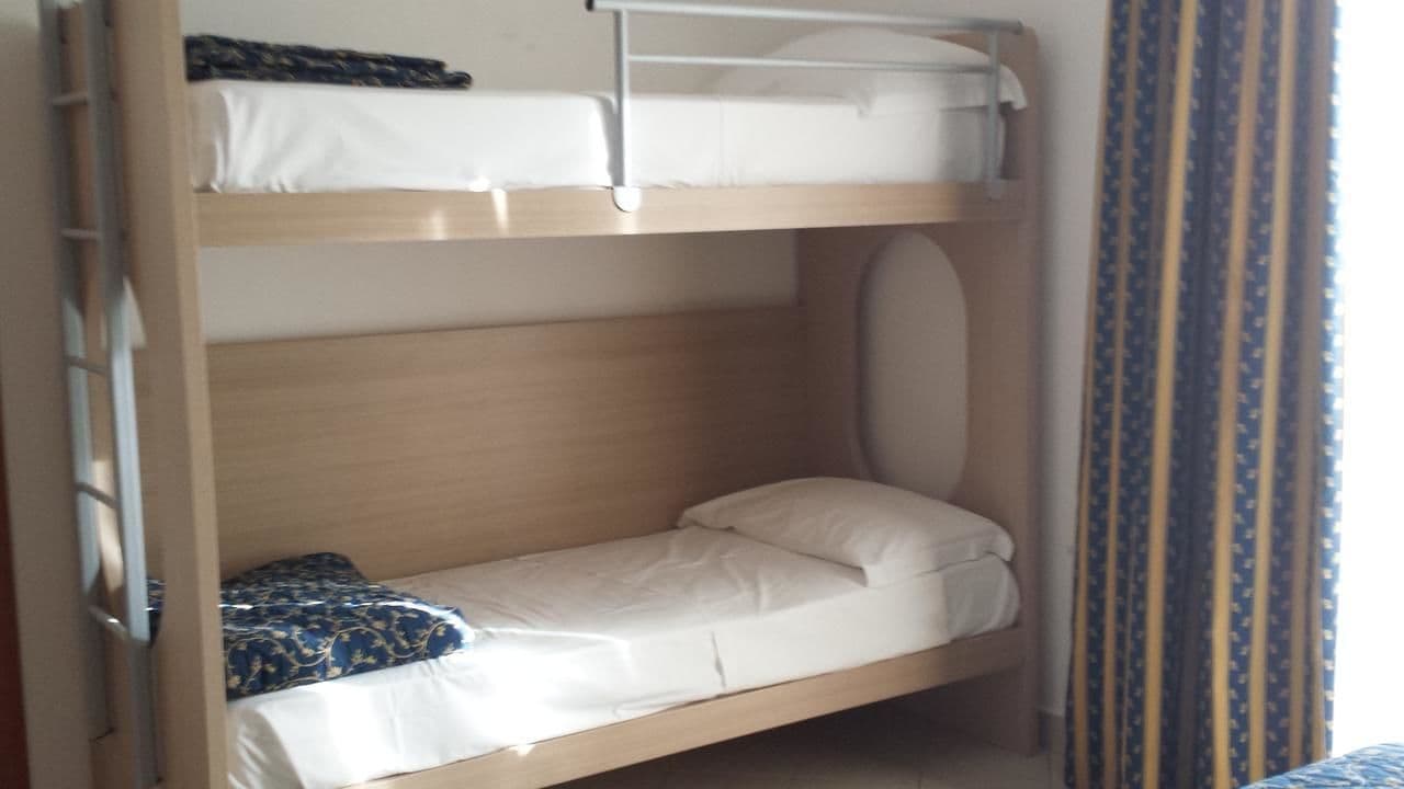 A bunk bed with two levels, each with a pillow and a blanket.