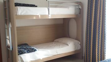 Un lit superposé à deux niveaux, chaque niveau étant équipé d’un oreiller et d’une couverture.