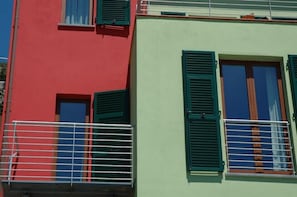 A two-story building with green shutters and white railings.