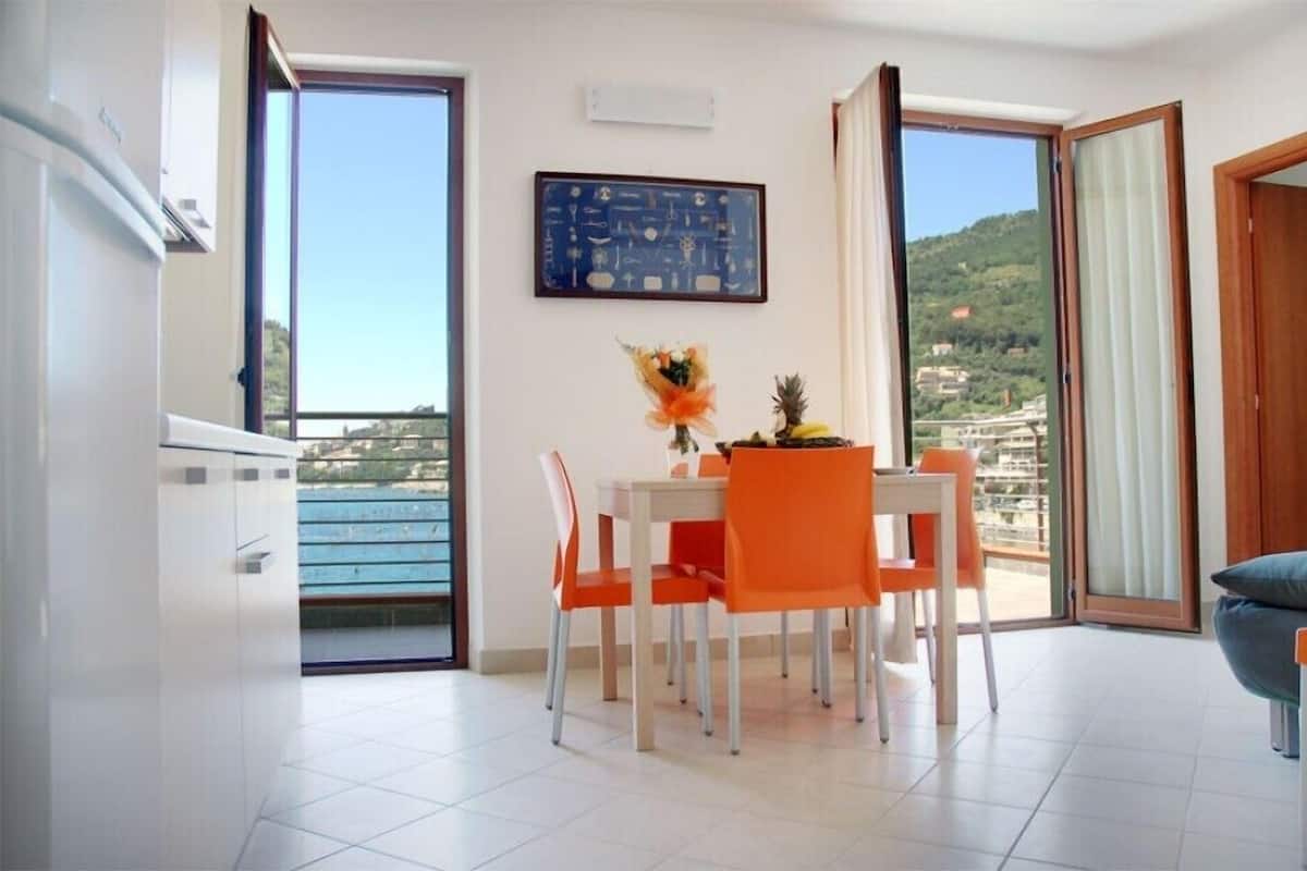 Een eethoek met een tafel en stoelen, uitzicht op een balkon en een lijst met een afbeelding aan de muur.