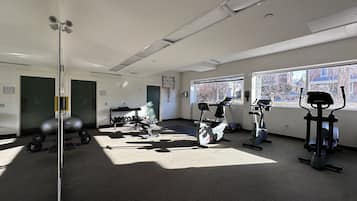 Ein Fitnessraum mit Trainingsgeräten, einem Spiegel und einem Fenster mit Blick nach draußen.