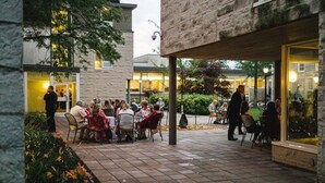 Un espace extérieur aménagé en terrasse, avec des tables et des chaises, entouré de murs en pierre et de verdure.