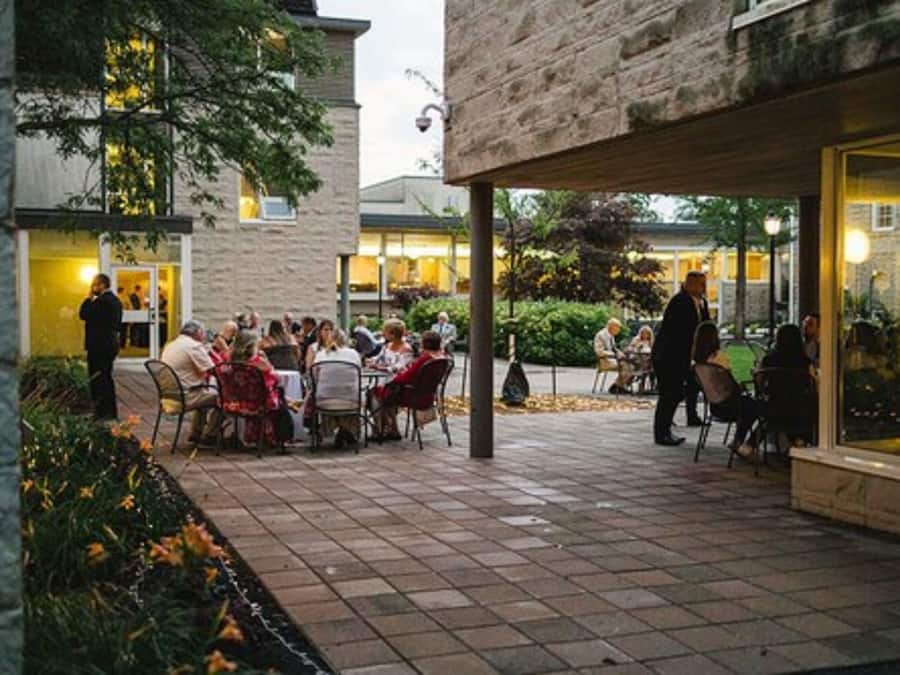 Un espace extérieur aménagé en terrasse, avec des tables et des chaises, entouré de murs en pierre et de verdure.