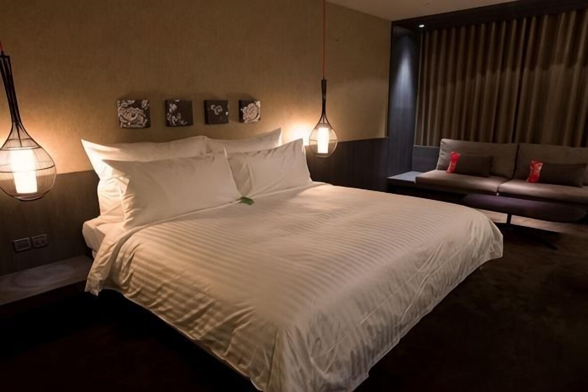Una habitación de hotel con una cama grande, un sofá e iluminación empotrada.