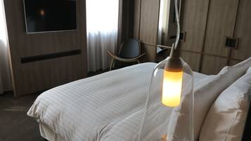 A hotel room with a large bed, a TV mounted on the wall, and a chair.