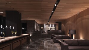 A modern lobby with a marble floor, leather seating, a reception desk, and a kitchen area in the background. - Hotel Dua (Kaohsiung)