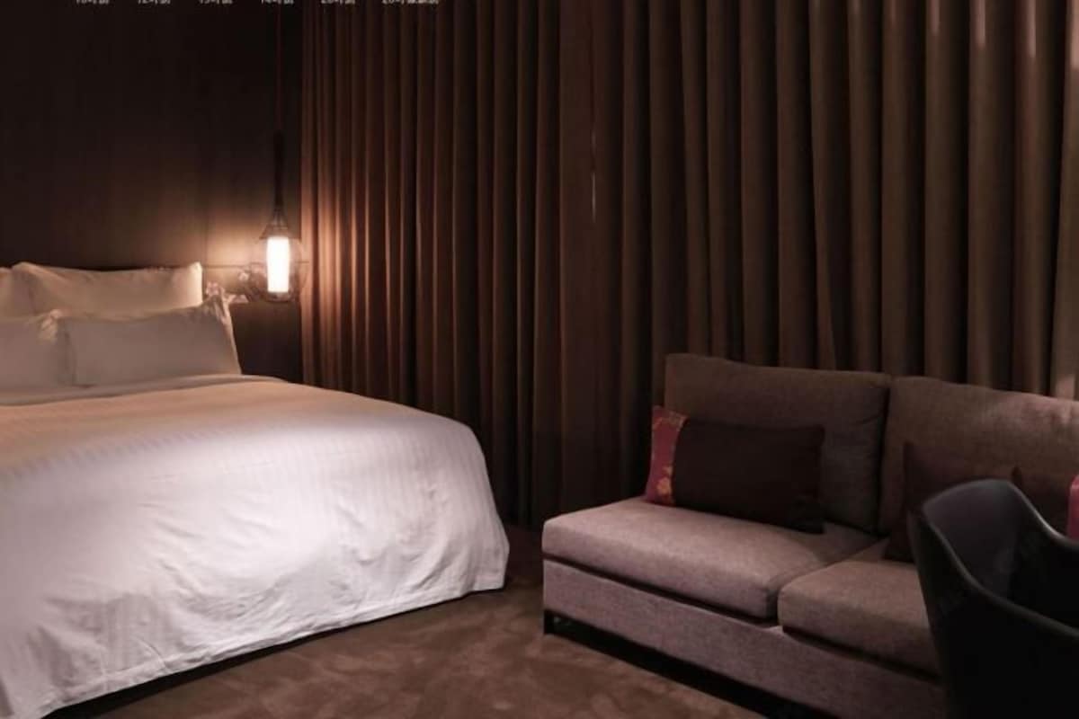 Une chambre d’hôtel avec un lit, un canapé et un mur équipé de stores verticaux.