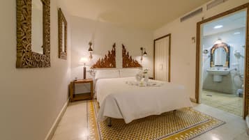 A hotel room with a bed, a nightstand, a mirror, and a bathroom visible through an open door.