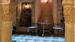 An interior with a checkered floor, a central seating area with chairs, and ornate arches. - Hotel Argantonio (Cádiz)
