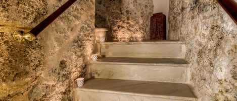Unos escalones de piedra conducen a una habitación con pared texturizada y un pomo de madera.