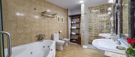 A bathroom with a large bathtub, a toilet, a sink, and a shower area.