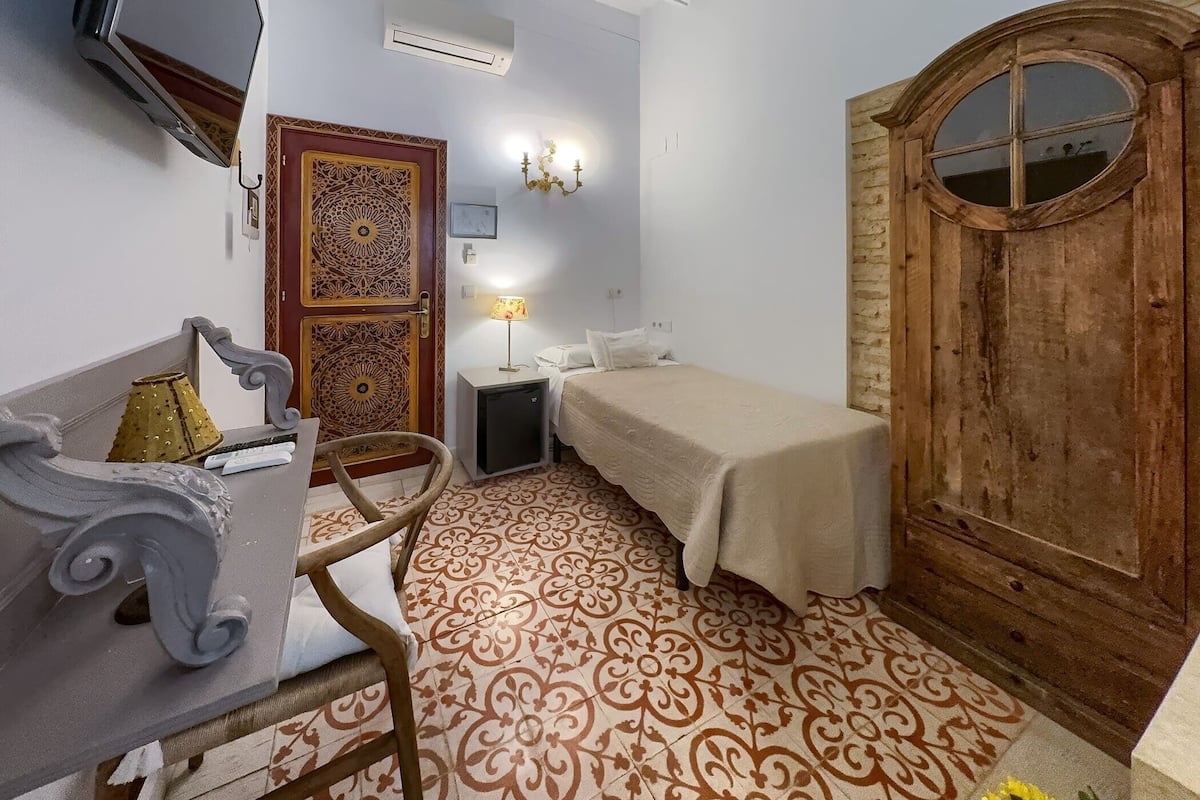 A room with a bed, a desk, a chair, a lamp, and a decorative door.