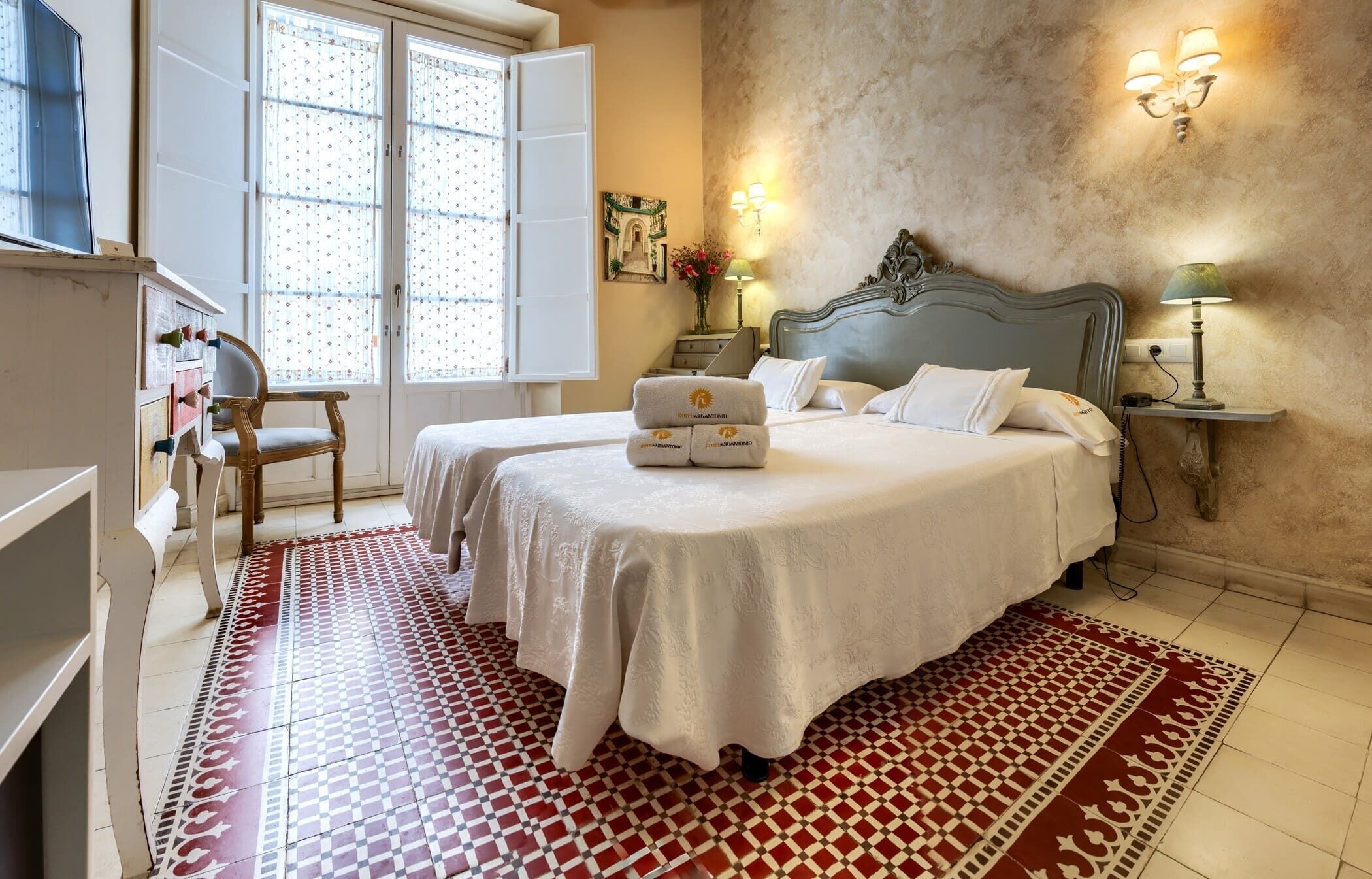Un dormitorio con una cama grande, una silla, un escritorio y una ventana con cortinas.