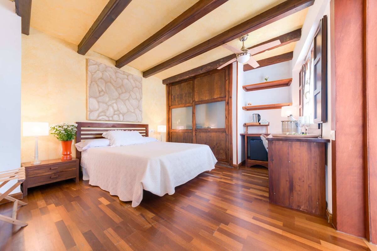A bedroom with a wooden bed, a nightstand, a dresser, and a built-in desk with a chair.