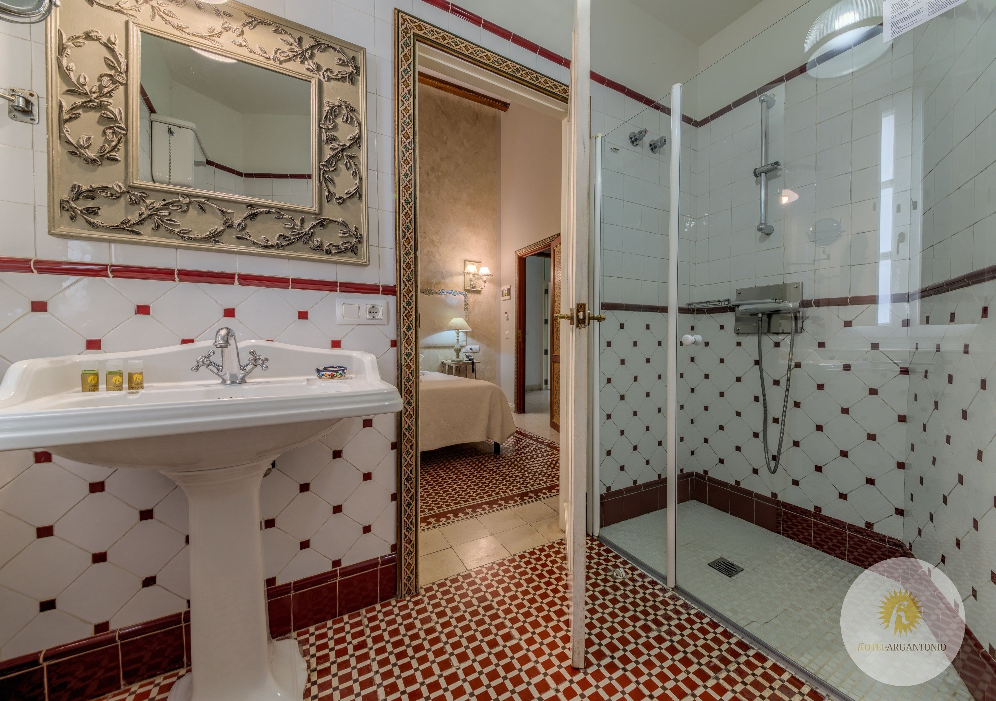 Een badkamer met een wastafel, spiegel, douche en betegelde vloer.