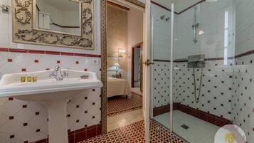 Une salle de bain avec un lavabo, un miroir, une douche et un sol carrelé.
