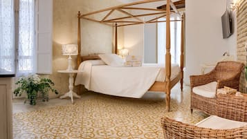 Un dormitorio con una cama con dosel, una silla de mimbre, una mesita de noche y un espejo grande.