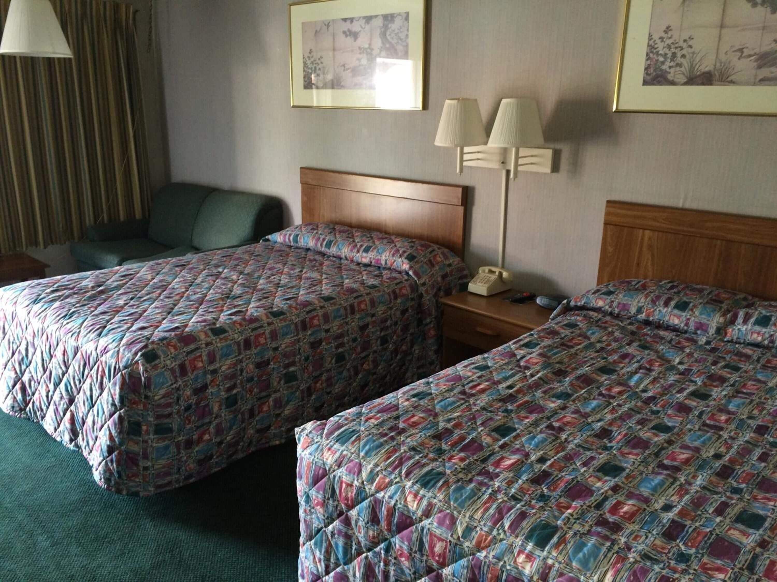 Een hotelkamer met twee bedden, een bureau, een stoel en een lamp.